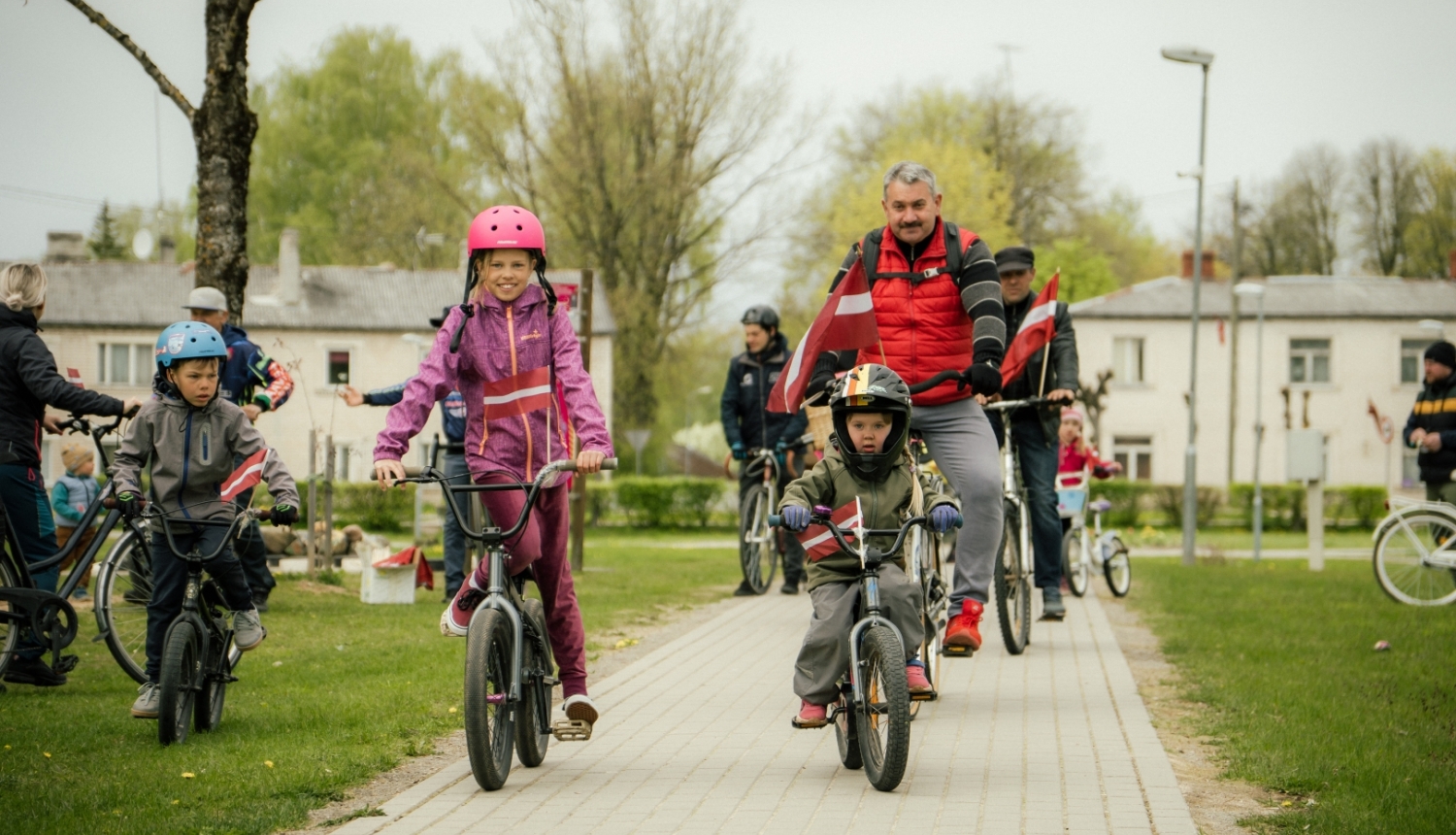 Neretas apvienības pārades vaītājs un bērni 4. maija velo braucienā ar Latvijas karogiem